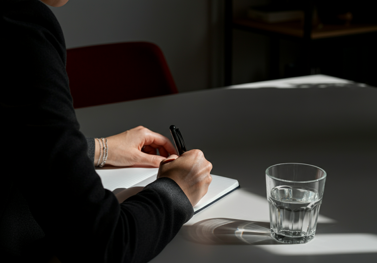 A person is thoughtfully writing or journaling, perhaps listing anxious thoughts or practicing cognitive reframing.