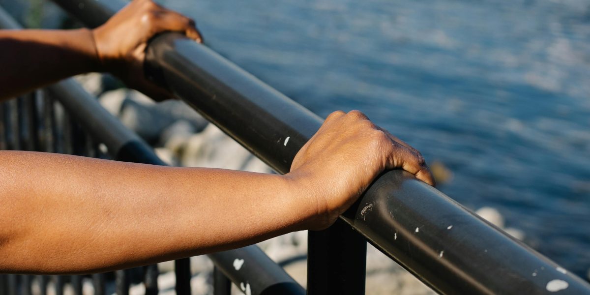 A person gripping a railing on a high place, showing signs of nervousness and fear of heights.