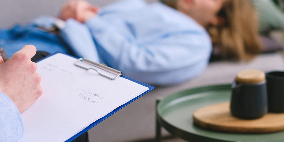 A person writing notes during a therapy session, focusing on strategies to manage thoughts and behaviors.