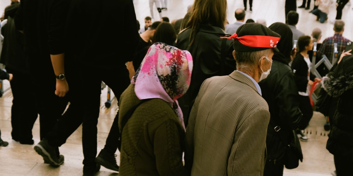 A person hesitating at the edge of a bustling public square, illustrating the avoidance characteristic of agoraphobia.