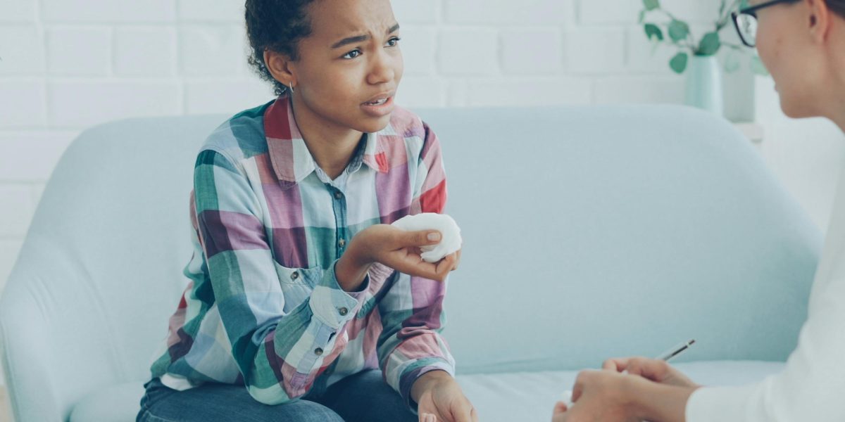 A person engaged in a therapy session, actively communicating with a counselor, representing the importance of psychosocial interventions in treatment.