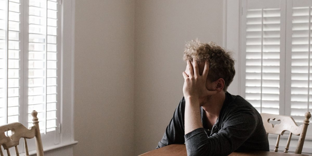 A person appears deep in thought or feeling overwhelmed, reflecting the confusion and stigma often associated with mental health conditions like schizophrenia.